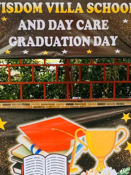 A graduation day backdrop for a school and daycare, complete with a custom banner and star-shaped foil balloons.
