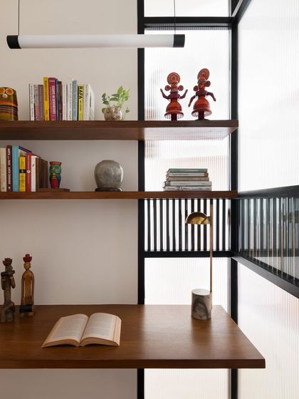 This study pod features a floating teak desk and shelves. The design maximizes a small space, creating a functional work area that feels open and integrated with the room's architecture.