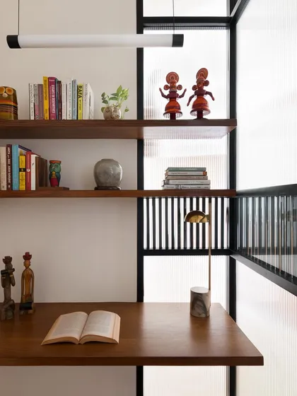 This study pod features a floating teak desk and shelves. The design maximizes a small space, creating a functional work area that feels open and integrated with the room's architecture.