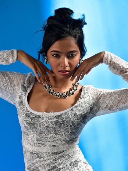 This symmetrical pose with hands framing the chin creates a powerful and balanced composition. It's a modern, confident way to showcase a classic jewelry set.