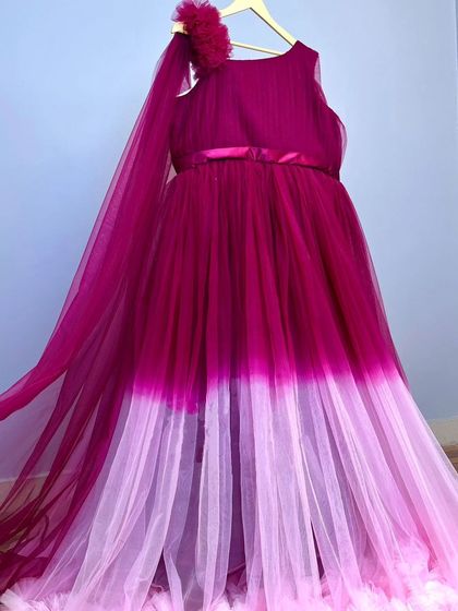 This beautiful ombre gown transitions from magenta to a soft lilac. The flowing tulle and one-shoulder detail make it an elegant and modern choice for a photoshoot.