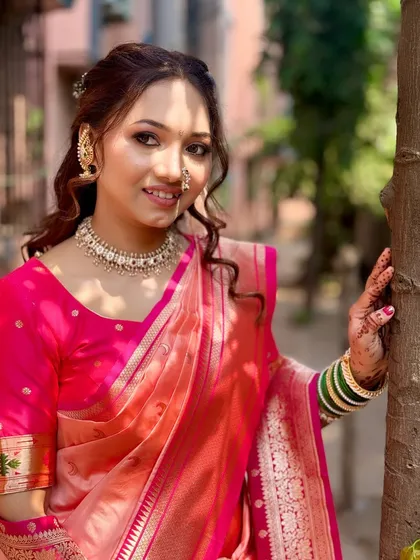 Posing outdoors, her makeup and hair look flawless. The half-up hairstyle with soft curls is a popular choice for engagement ceremonies.