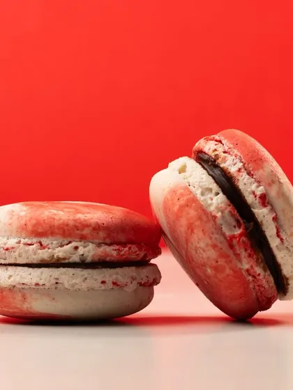 A pair of festive Christmas macarons from Bené. The clean, simple composition against a red background makes the product pop.