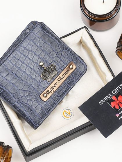 A blue crocodile leather wallet personalized with a crown charm and a full name engraving.