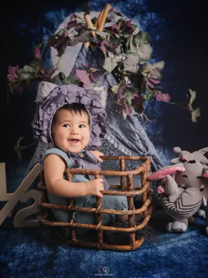 Celebrating the half-birthday milestone at six months old. This happy baby sits in a wicker basket with a '1/2' sign, showing off a huge, infectious giggle.