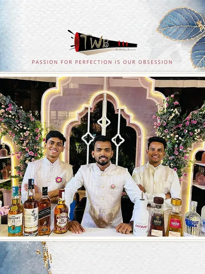 Our team of bartenders posing behind a beautifully decorated bar at The Leela Palace, ready for a grand wedding reception.