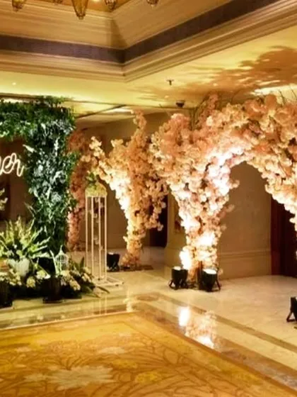 A wide view of an engagement party entrance. The 'Better Together' neon sign is complemented by arches of artificial cherry blossoms, creating a stunning welcome for guests.