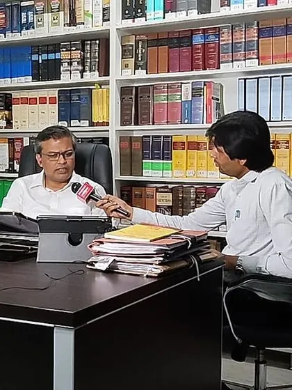Conducting a formal interview in my office library, providing an in-depth legal perspective on a complex criminal case for a news channel.