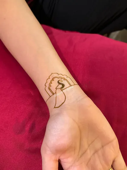 The initial outline of the 'S' initial and peacock feather design.