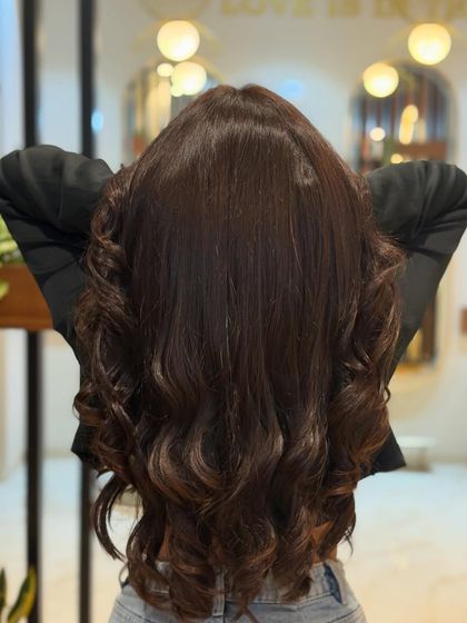 The back view of a stunning coffee mocha global color. The rich tone is even from root to tip, and the bouncy curls show off its incredible shine.