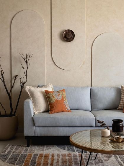 This shot focuses on the layered textures and colors, with the pale blue sofa set against a wall of arched grooves and a sculptural dried branch arrangement.