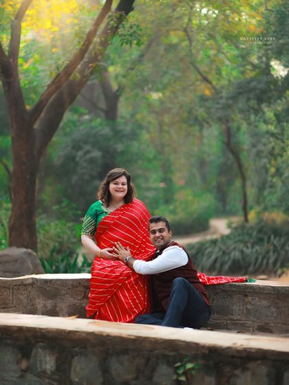A joyful and relaxed pose on a park bridge. The husband-to-be lovingly holds the baby bump, sharing in the excitement.