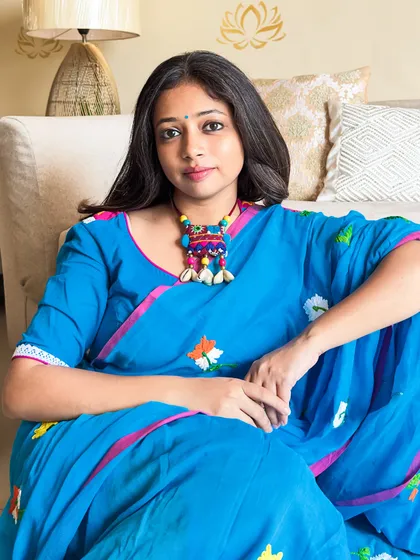 A simple, clean portrait. The focus is on the beautiful color of the saree and the feeling of comfort and ease.