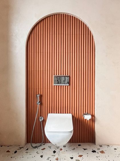 Even the smallest details are considered. This toilet niche features a fluted terracotta-colored wall, continuing the home's theme of curves, texture, and earthy tones.