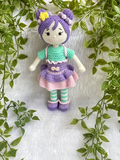 A beautiful doll with purple hair buns and a tutu dress. She also comes with a tiny backpack for her adventures. The striped stockings are attached, but her dress and shoes are removable.
