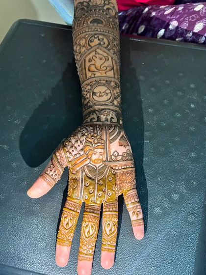 The completed groom portrait on the bride's palm, part of a full bridal design that tells their unique story.