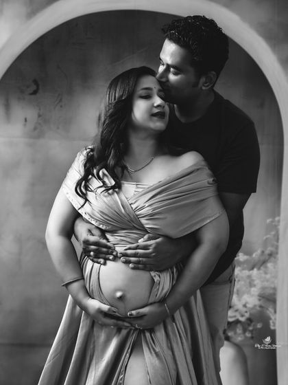 A timeless black and white portrait of a couple's embrace. The focus is purely on the emotion and connection as they hold the baby bump together.
