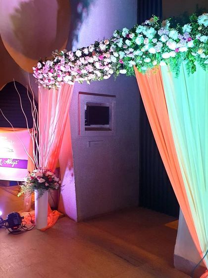 A wider view of the colorful draped entrance. The lighting enhances the colors of the fabric and flowers, creating a warm and inviting atmosphere for the wedding celebration.