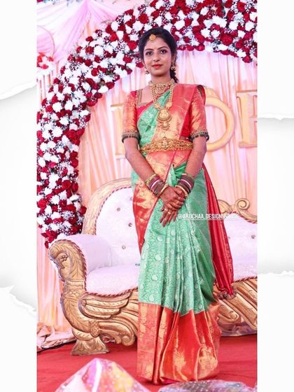 A full-length view of a client on her engagement day. She is wearing a beautiful sea green and red Kanjivaram saree paired with a custom-designed blouse with detailed handwork on the sleeves.
