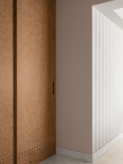 A detail of the material palette, with cork-paneled doors and fluted walls adding texture and warmth to the corridor.