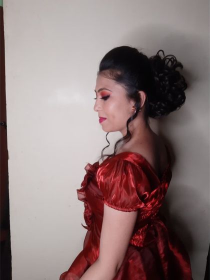 The side profile shows the elegant curly updo with loose tendrils framing the face. This hairstyle is a great choice for off-the-shoulder gowns.