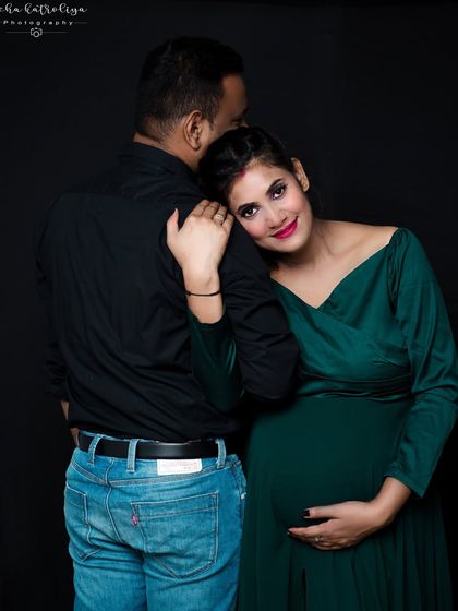 Sometimes the most powerful images are the quiet ones. Here, the mother-to-be rests her head on her partner's shoulder, creating a moment of serene connection. The dark background and rich green dress make the portrait feel intimate and classic.