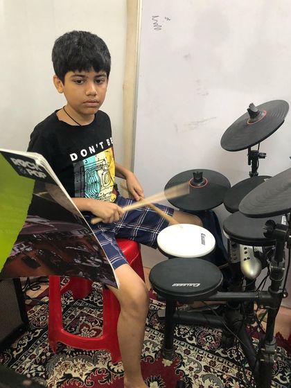 A young drummer sits at his kit, ready for his lesson. His focus and determination are exactly what's needed to master this powerful instrument.