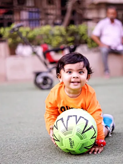 A happy toddler crawls on the grass with a bright green soccer ball, capturing a moment of pure, playful energy.