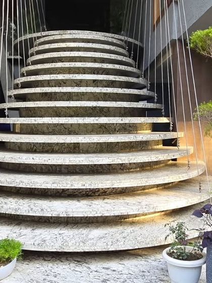 This sculptural staircase appears to float, suspended by cables and surrounded by lush greenery. It's not just a way to move between floors but an artistic feature that integrates landscaping into the core of the home.