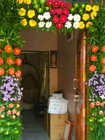 A housewarming flower decoration for a door. The arch is made of lush greenery and colorful flowers, creating a natural and beautiful entrance.