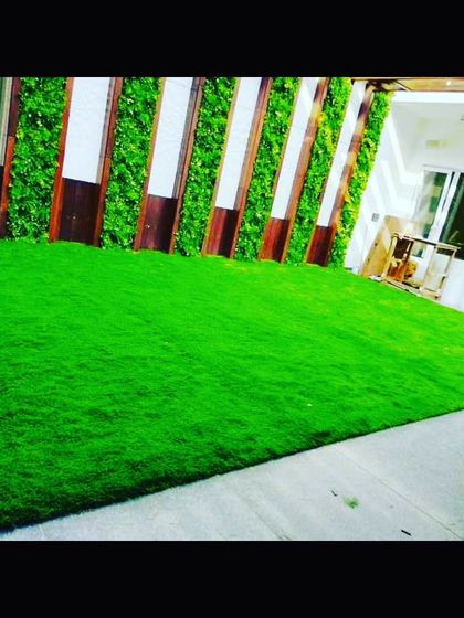 This indoor or covered patio area uses artificial grass to bring the outdoors in. It's paired with a wood and green panel wall for a complete garden look.