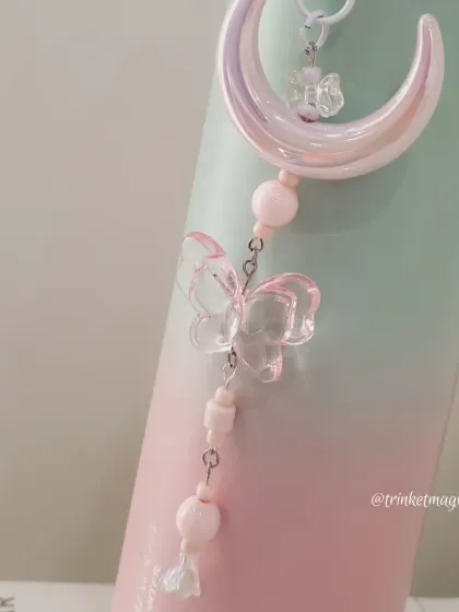This image shows the pink moon and butterfly charm attached to a water bottle, demonstrating its versatility. It's a great way to personalize your everyday items.
