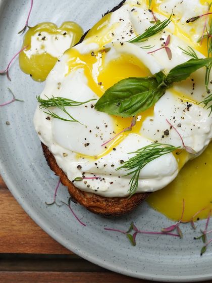 A close-up of our Turkish Toast, with its perfectly runny egg yolk, fresh dill, and basil over garlicky yogurt.