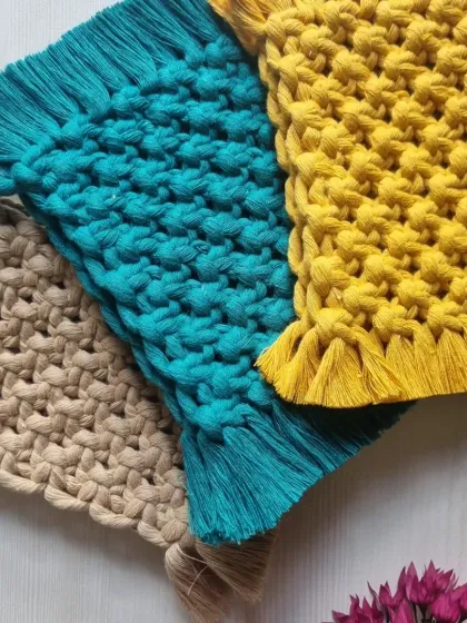 My rectangular macrame coasters, shown here in beige, teal, and yellow. The dense, textured knot pattern is highly absorbent and durable.