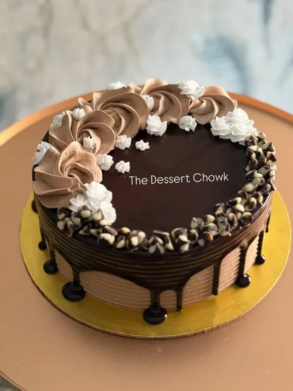 A delicious chocolate drip cake with a mix of chocolate and vanilla cream piping and chocolate chips.