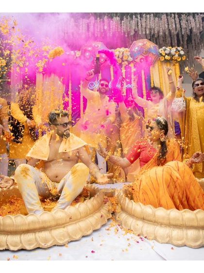 An explosion of color and joy as Akshat and Divyanshi are showered with flower petals and colored powder by their guests.
