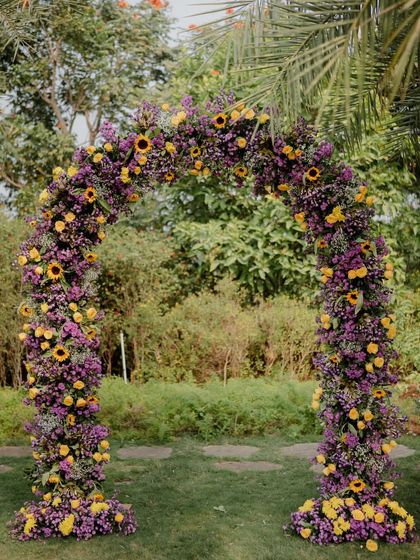 A whimsical floral arch created for an outdoor Mehendi. We used a lush combination of sunflowers, marigolds, and rich purple blooms to craft a vibrant and enchanting gateway for guests.