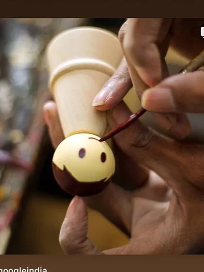 A close-up of an artisan's steady hand painting a cheerful face onto a wooden doll. This delicate work requires immense precision and is what gives our toys their distinct character and charm.