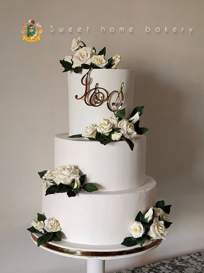 Simplicity at its finest. This three-tiered white wedding cake is adorned with clusters of beautiful white sugar roses and a custom gold monogram topper. It’s an elegant and sophisticated design that speaks volumes.