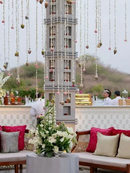 A comfortable and stylish lounge seating area at a Leela Palace Udaipur event, with a stunning central tower and hanging floral strings. We design functional spaces that encourage guest interaction without compromising on aesthetics.