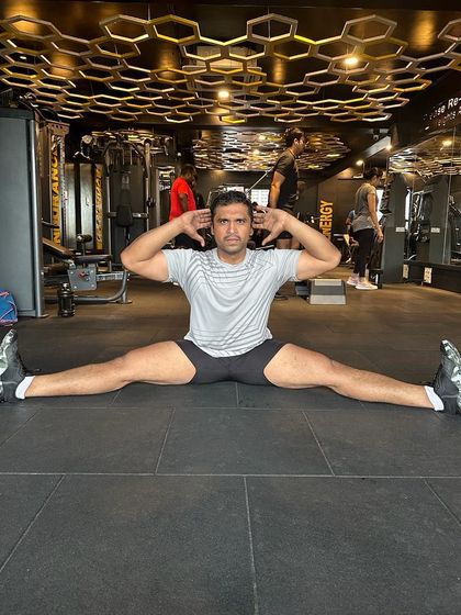 Flexibility is just as important as strength. This member is demonstrating incredible flexibility with a full split, a result of consistent stretching and dedication to all aspects of fitness.