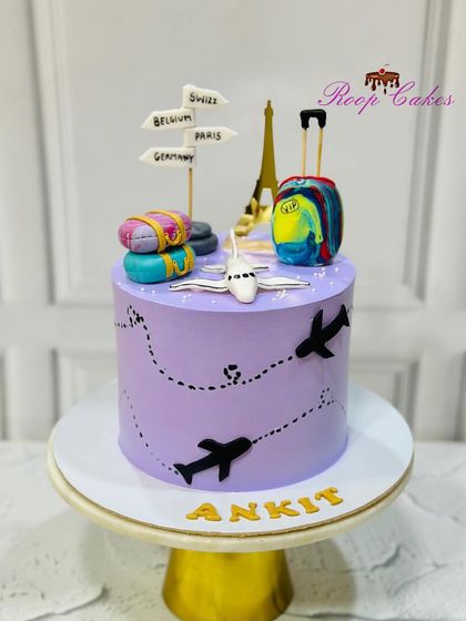 A semi-fondant travel theme cake for Ankit. This purple cake is decorated with airplane silhouettes and topped with a fondant plane, luggage, and signs pointing to dream destinations.