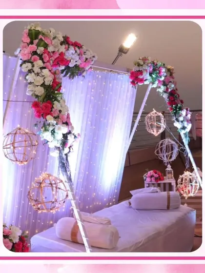 A cozy VIP lounge area at a pink-themed wedding. The decor includes a floral arch and hanging lanterns over a comfortable seating arrangement.