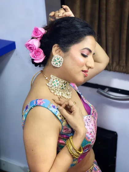 A glamorous look for Kavya for a festive event. This look features a colorful lehenga, statement jewellery, and a soft, romantic updo with fresh roses.
