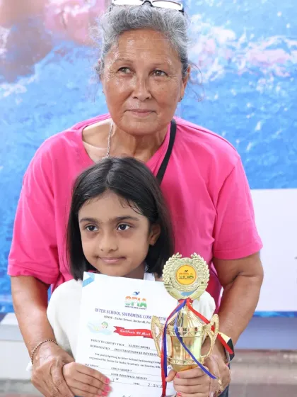 A grandmother proudly stands with her granddaughter, a trophy winner at our event. Our competitions bring together generations of supporters.