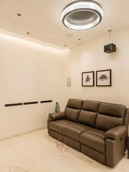 A full view of the home theater, showing the comfortable reclining sofa, the ceiling-mounted projector, and the discreetly placed surround sound speakers. Every element is designed for optimal viewing and comfort.