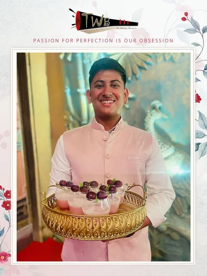 A smiling bartender serves a tray of delicious grape mocktails, providing excellent service to guests at a large reception.