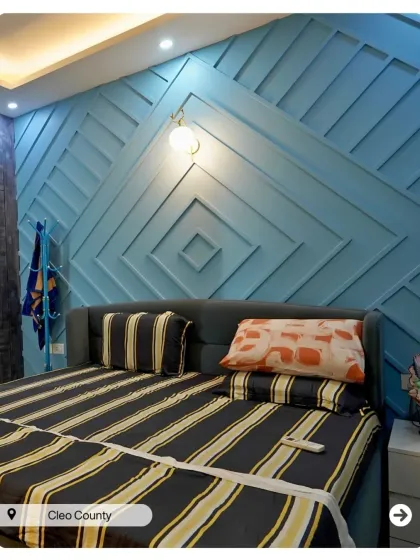 A bedroom with a bold, geometric accent wall in a cool blue. The design is modern, playful, and adds a strong graphic element to the room.