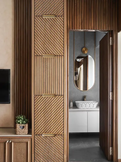 A view of the parent's bedroom, showing the custom wardrobe with its intricate wood grain and fluted patterns, leading into the ensuite bathroom.