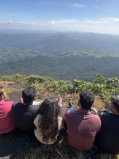 A moment of quiet contemplation as trekkers sit and gaze at the endless layers of hills from a viewpoint.